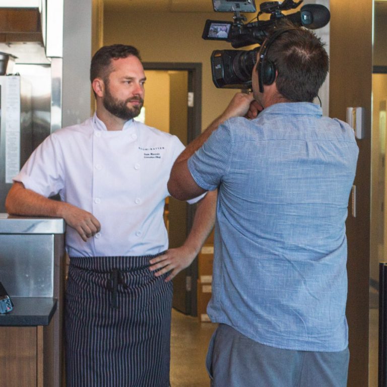 A chef being filmed by a cameraman.